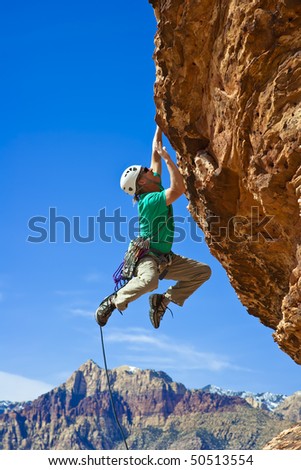 Male rock climber  clings to an overhang in Red Rock Canyon on a sunny day.