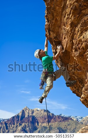 Male rock climber  clings to an overhang in Red Rock Canyon on a sunny day.