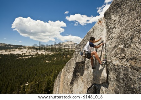 Male climber grips and scampers up a sheer rock wall in Yosemite\'s high Sierra Nevada mountains.