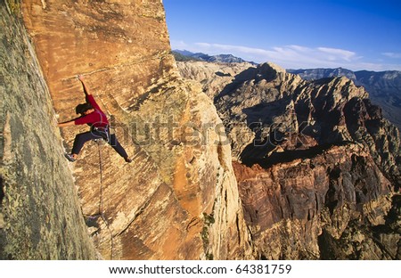Rock climber struggles for his next grip on a sandstone cliff.
