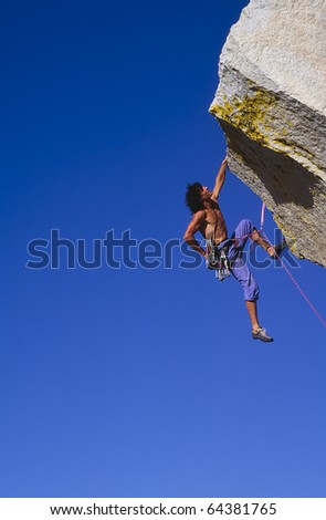 Rock climber struggles for his next grip on a overhanging cliff.