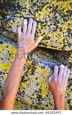 Rock climber reaching for the next hand hold on a steep wall.