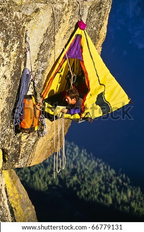 Rock climber bivouacked in his portaledge on an overhanging cliff.