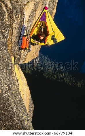 Rock climber bivouacked in his portaledge on an overhanging cliff.