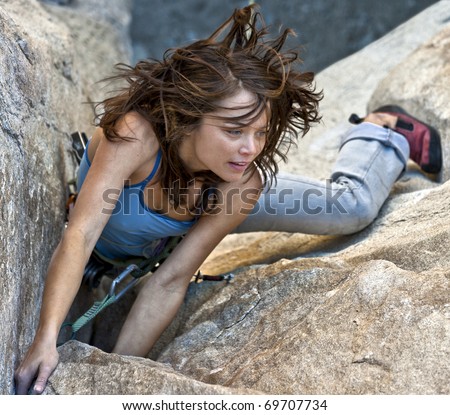 Female rock climber struggles to reach her next grip as she battles her way up a steep cliff in Joshua Tree National Park, California.