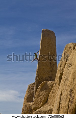 Male climber struggles to reach his next grip as he battles his way up the edge of rock pinnacle.