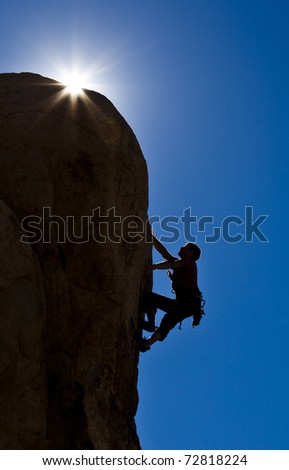 Male climber struggles to reach his next grip as he battles his way up the edge of rock pinnacle.