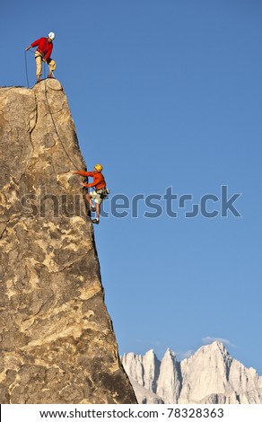 Team of climbers struggle to reach the summit of an challenging rock pinnacle.