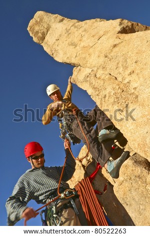 Team of rock climbers struggle to reach the summit of a steep pinnacle.