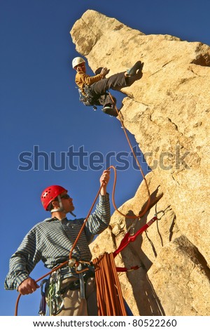 Team of rock climbers struggle to reach the summit of a steep pinnacle.