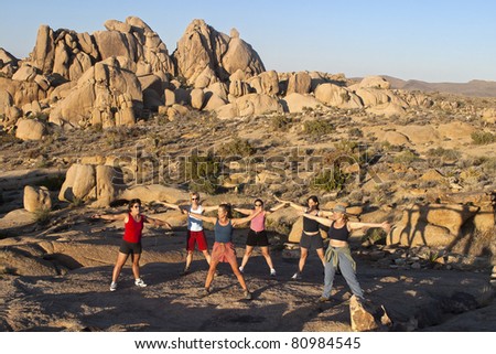 Female hiking team stretches after climbing to  the summit of a challenging rock spire in Joshua Tree National Park.