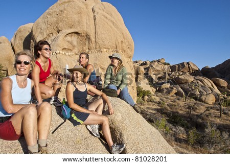 Female hiking team climbs to the summit of a challenging rock spire in Joshua Tree National Park.