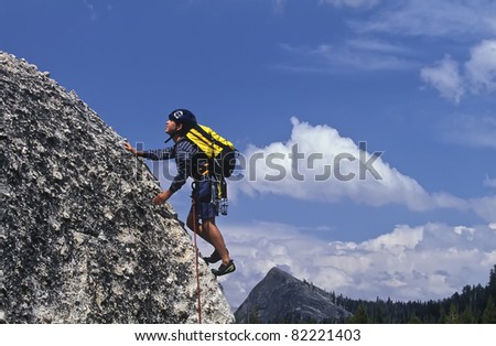 Young male climber struggles up  a challenging rock wall.