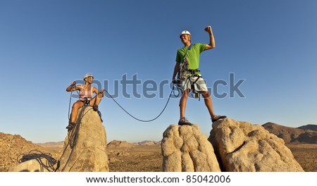 Team of rock climbers struggle to the summit of a challenging cliff.