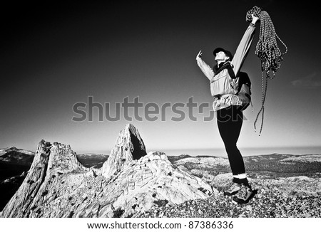 Female climber celebrates on the summit of a challenging and remote mountain after a successful ascent.