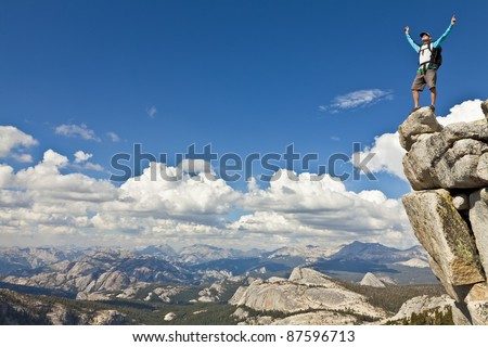Male rock climber celebrates on the summit after a successful ascent.
