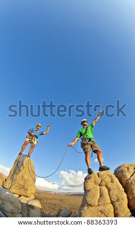 Team of climbers celebrate on the summit of a rock pinnacle after a challenging ascent.