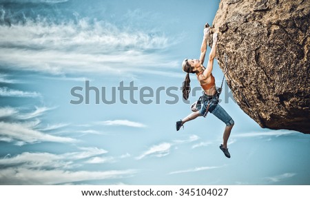 Female rock climber struggles to reach her next grip as she battles her way up a steep cliff in Joshua Tree National Park, California.