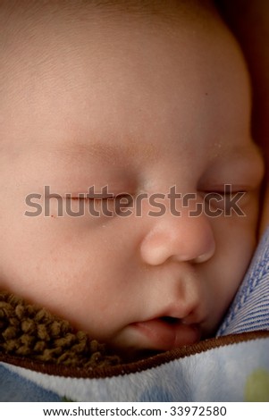 A close up of a sleeping newborn wrapped in a blanket.