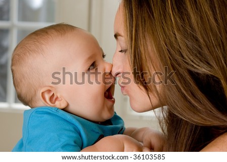 A baby and mother touching noses.  Baby is laughing.