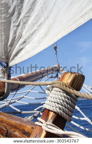 Sailboat in action, big white sail raised over blue clear sky