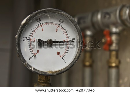 Industrial pressure meter - barometer and water pipes in the background