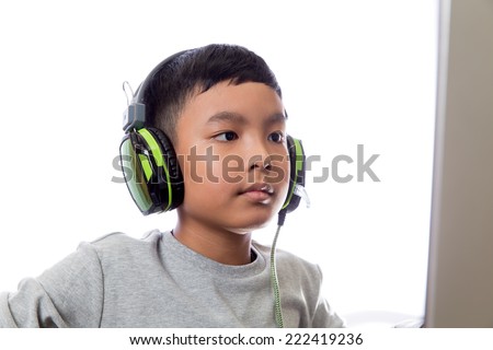 Asian kid play computer internet games and wear headset to communicate