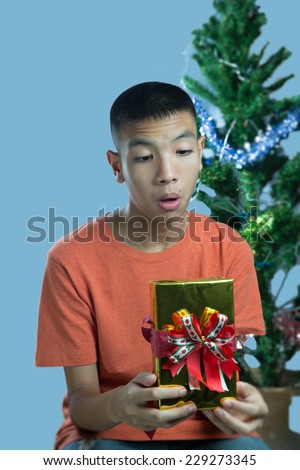 Young asian teenager surprise to get a gift on blue background