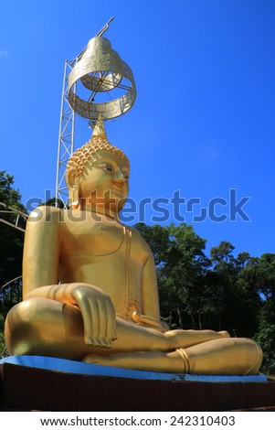 The golden image of Buddha in public temple which have Thai art umbrella over the head.