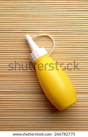 yellow sauce bottle on bamboo matt in dry paint