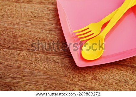 plastic plate spoon ann fork are on wooden background