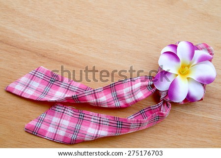 pink fabric hair band with purple flower on wooden background