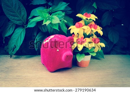 piggy bank and flower vase on wooden ground in vintage tone