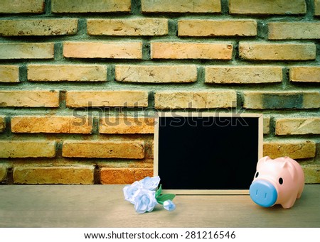 pink piggy bank and blackboard on old dirty brick wall background