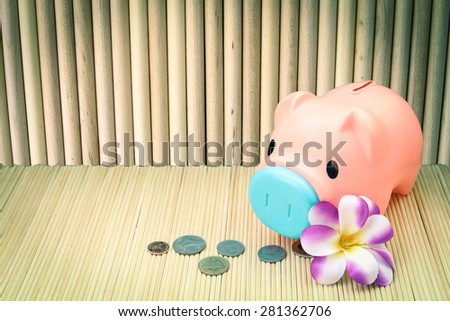 pink piggy bank and coin on round wooden wall background  in vintage tone