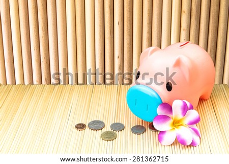 pink piggy bank and coin on round wooden wall background  in vintage tone