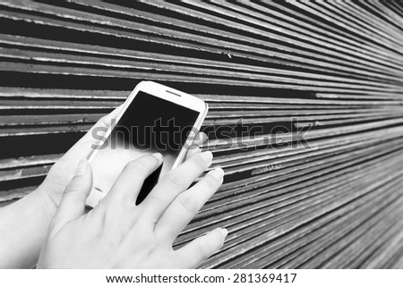 blur hand using mobile phone on blur roof-tile stacking background  in black and white tone