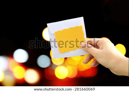 hand holding yellow card and white envelope on bokeh from traffic light background