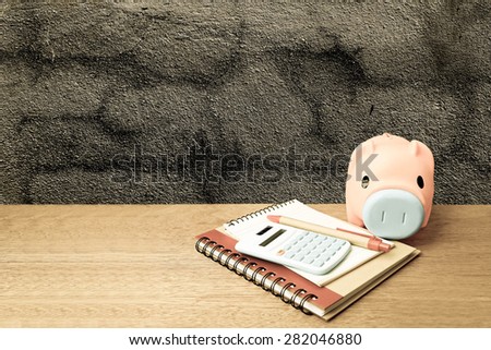 piggy bank calculator and writing tools on dark crack wall background