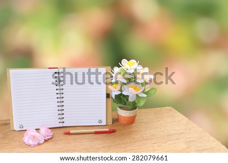 open notepad and flower vase on blur bokeh from bush background
