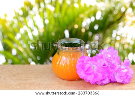 orange juice and pink flower on blur and bokeh from yellow palm leaf background