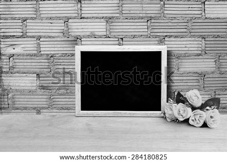 blackboard and bunch of roses on orange brick wall background