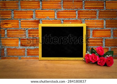 blackboard and bunch of roses on orange brick wall background