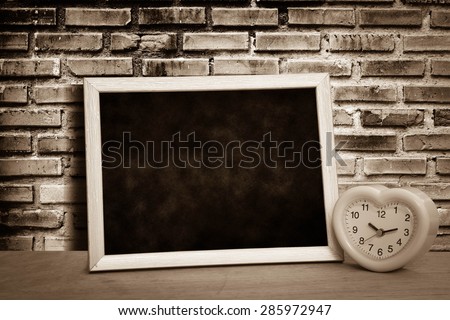 grunge blackboard and pink clock on old dirty brick wall background in vintage tone