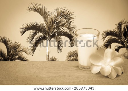 glass of milk and  flower with palm tree and  sky background  in vintage tone