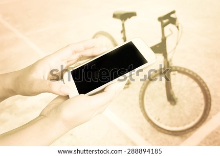 hand of child using mobile phone on blur bicycle on sport stadium background
