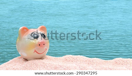 ceramic piggy bank on pink sea sand with blue ocean background