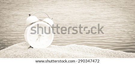 white clock on pink sea sand with blue ocean background