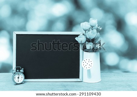 blackboard and watering pot vase on bokeh from tree background