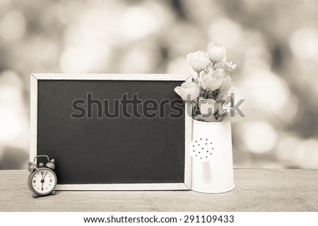 blackboard and watering pot vase on bokeh from tree background